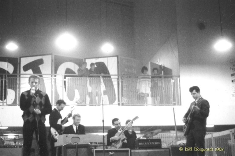 Black and White photo, 6 piece band with 4 audience members in the mezzanine above.