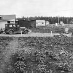 black and white photo of a house from June 30, 1949, with large garden up front. Various buildings are visible on the large property.