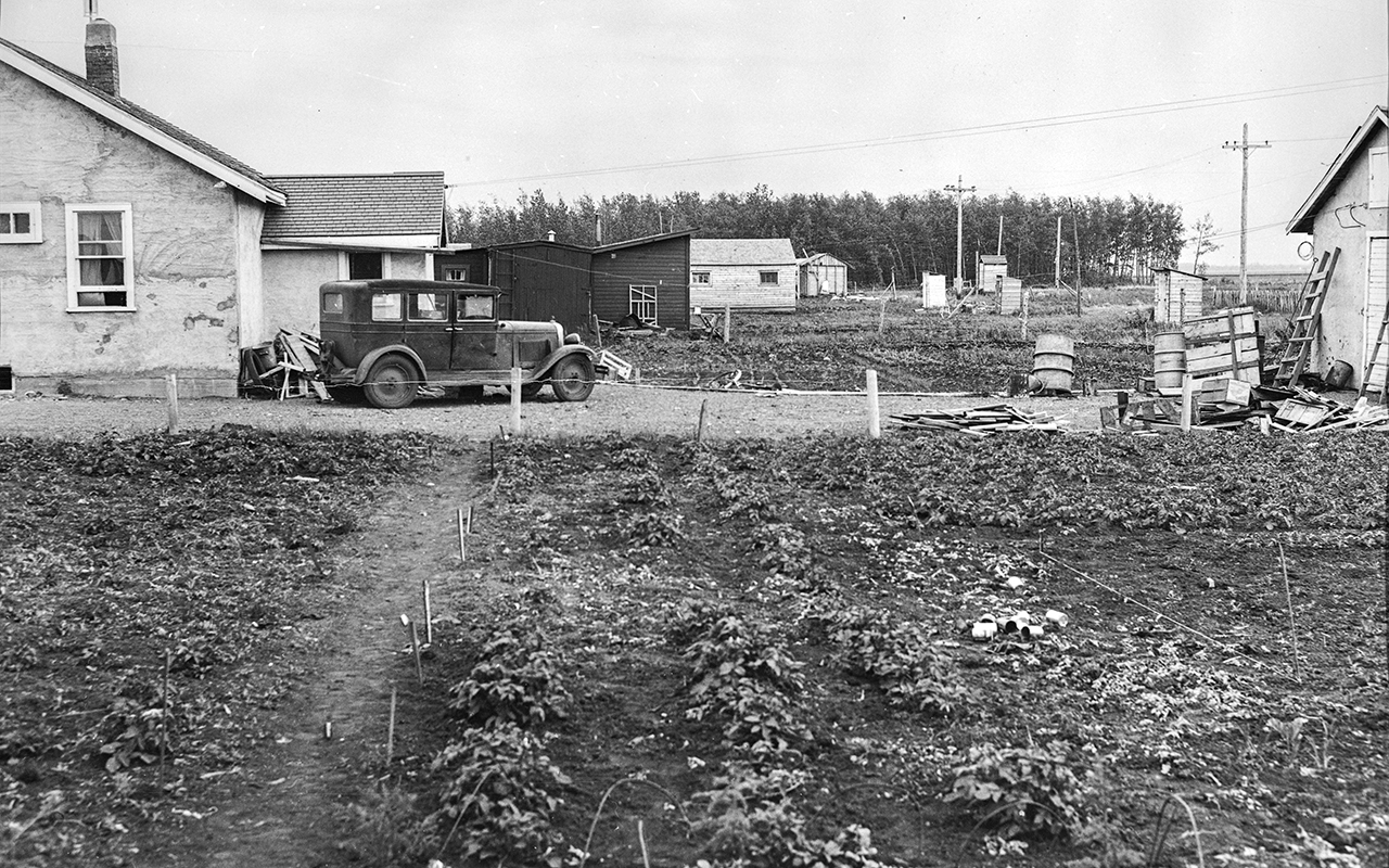 black and white photo of a house from June 30, 1949, with large garden up front. Various buildings are visible on the large property.