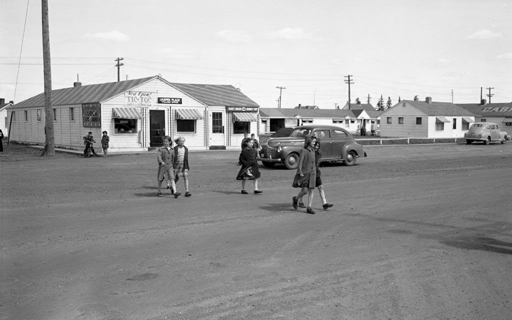 Students from West Jasper Place School head to school, crossing Stony Plain Road, 1950. Tic Toc Tailors in the background